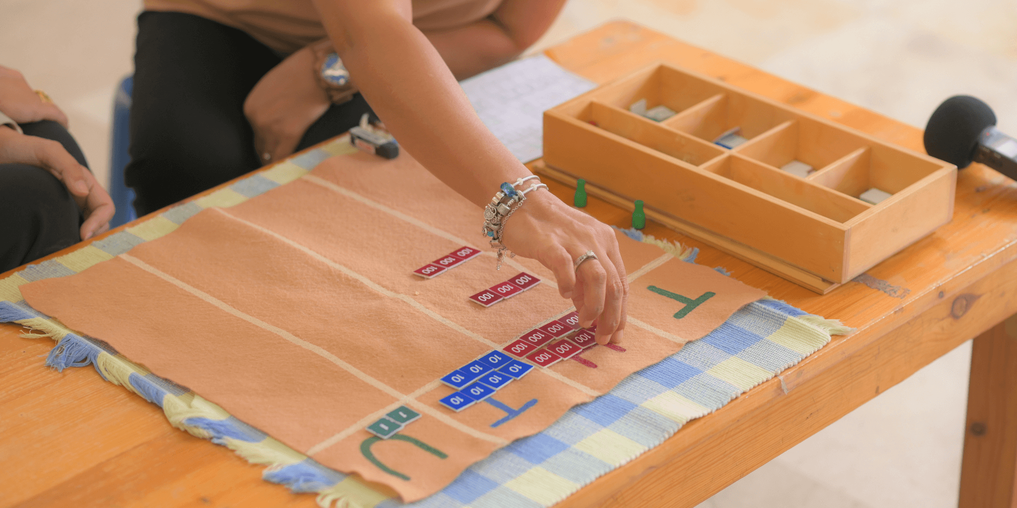 A Montessori trainee tries to work with the Montessori material after receiving a demonstration from her trainer. 