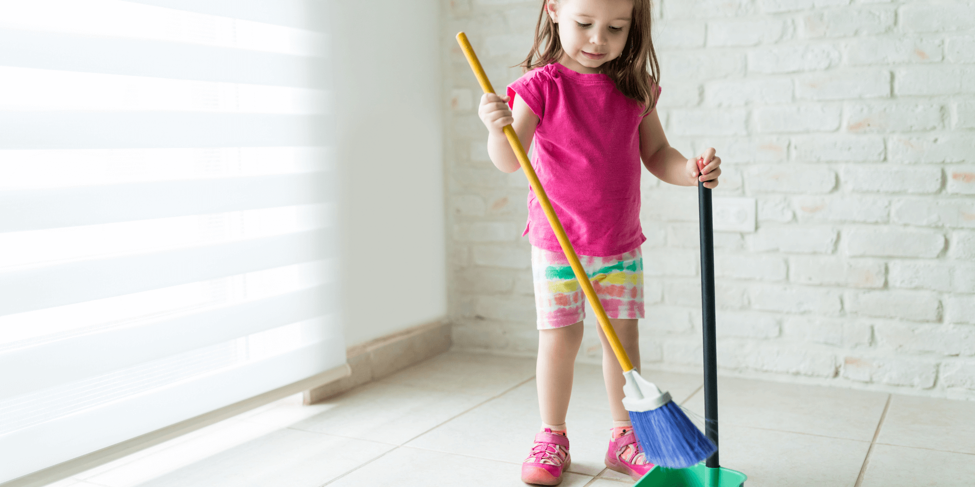 A young girl practices cleaning skills by sweeping in a Montessori classroom, learning responsibility and contributing to a tidy learning space.