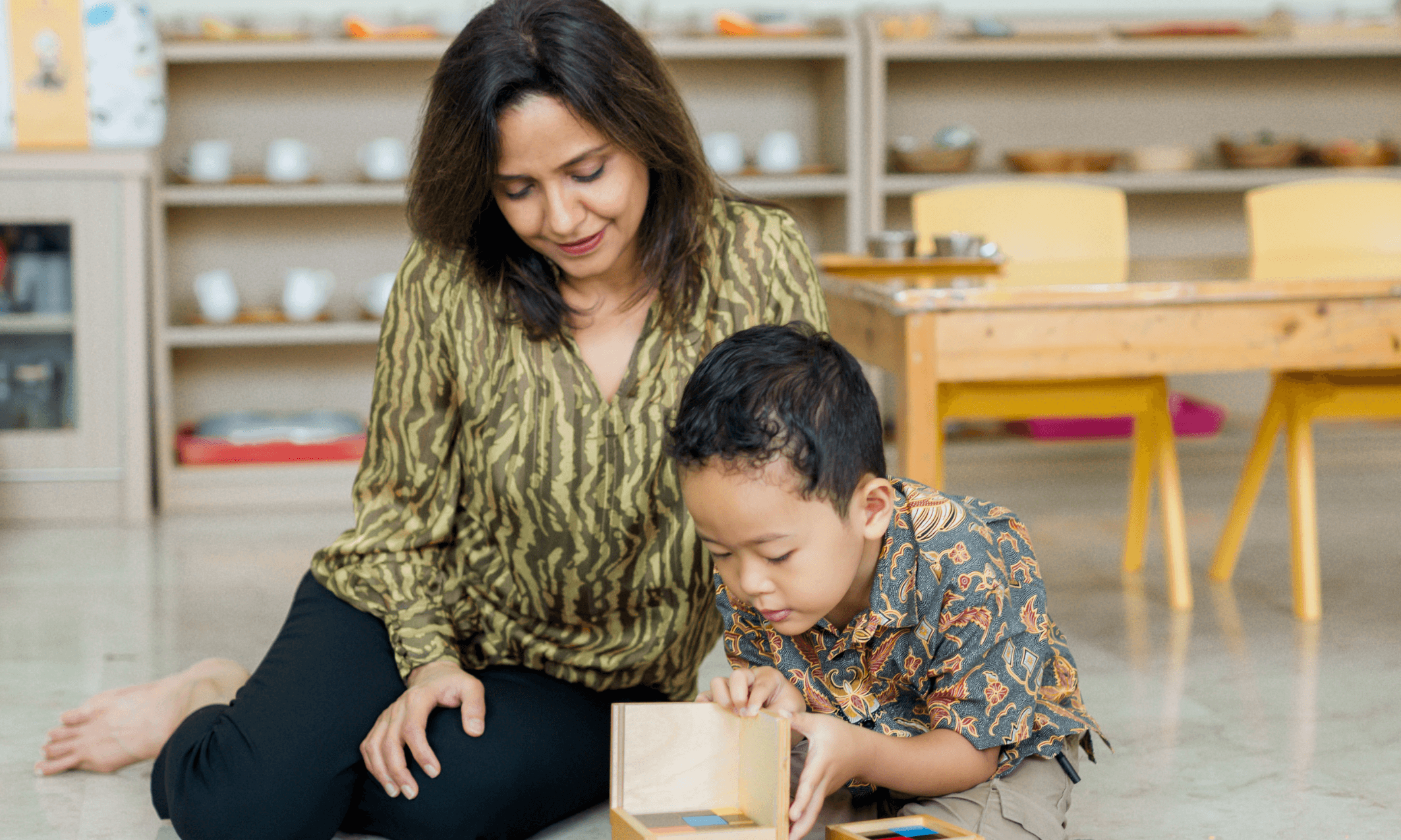 A Montessori teacher observing a child engaged in an activity.