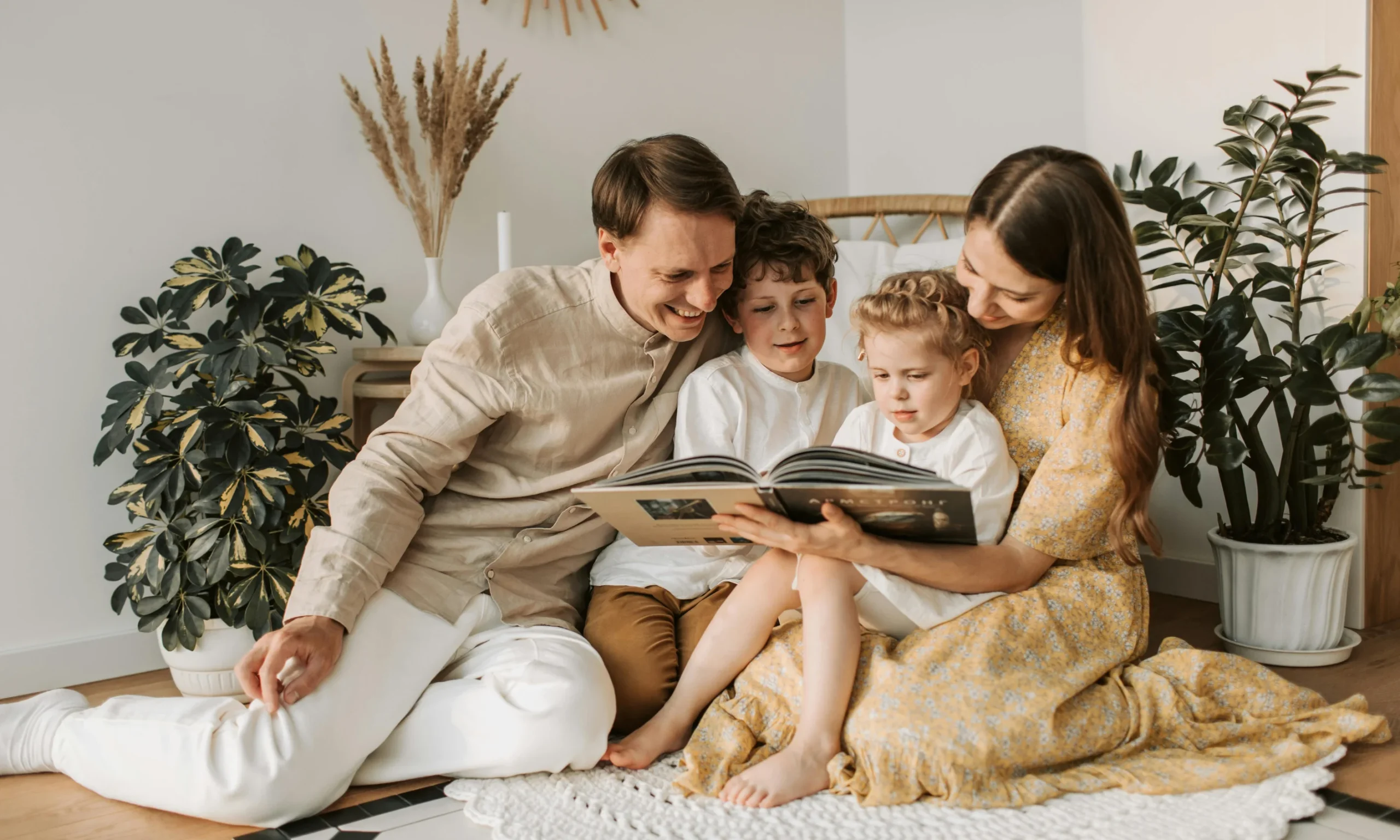 A family of four reading a book together in a bright, cozy room, demonstrating quality tech-free bonding time.