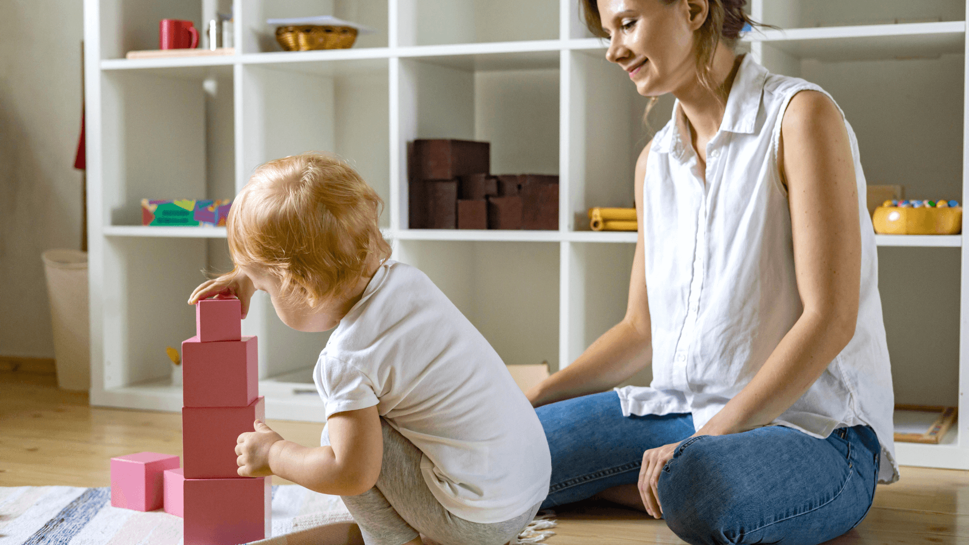 Girl working with Montessori pink tower, observed by her mom 